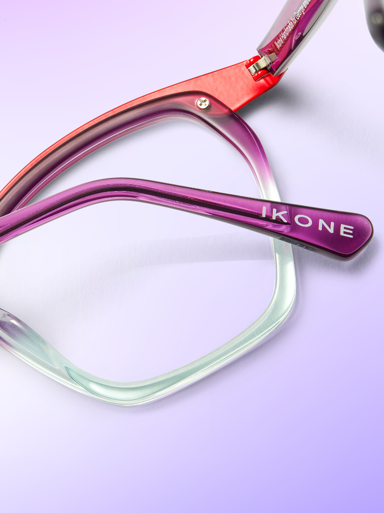 Close-up of purple and red eyeglass frames with the brand name "IKONE" on the temple, set against a gradient purple background.