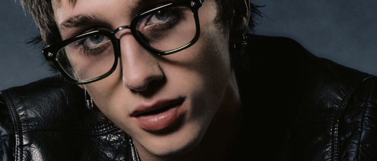 Portrait of a person with short dark hair wearing glasses and a black leather jacket.